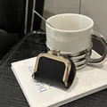 Mini black lychee grain leather coin purse with gold metal clasp on white book - Black