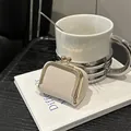 Mini porte-monnaie en cuir crème avec fermoir doré pour bijoux sur un livre - Blanc