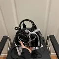 Black patent leather underarm bag with lace bows, metal chains, and cross charms - Black