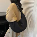 Borsa hobo nera opaca minimalista con tracolla regolabile indossata da una modella in maglia - Nero