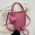 Borsa a secchiello rosa minimalista con ciondolo a cuore e dettagli dorati su tessuto bianco - Rosa