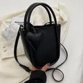 Borsa a secchiello in pelle nera con ciondolo a cuore, finiture oro e tracolla regolabile - Nero