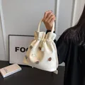 Elegante beige Leder-Beuteltasche mit dekorativen Strasssteinen und Tragegriff oben - Weiß