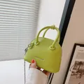Mini borsa a conchiglia verde con motivo litchi e catena argento in mano - Verde