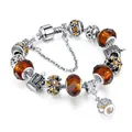 Silver snake chain bracelet featuring amber glass beads and sparkling crown charms - 17cm / Brown