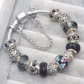 Dettaglio macro del bracciale con ciondoli in argento e perline floreali su velluto - Nero