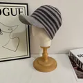 Detail of grey striped knit beanie with visor on a white display head in a studio setting - M / Gray