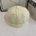 Dettaglio macro del cappello docker in tela beige con cuciture gialle a contrasto e strappi - Giallo
