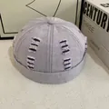 Dettaglio del cappello docker in denim lilla con bordi sfrangiati e cuciture a contrasto - Viola
