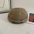 Detail van de katoenen docker muts met PROGRESS borduursel en gescheurde gaten - M / Khaki