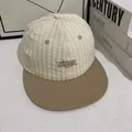 Primer plano de gorra de béisbol con logo bordado en marrón y visera plana suave - M / Blanco Roto