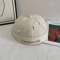 Detail of off-white cotton docker hat featuring Progress embroidery and distressed holes - M / Off White