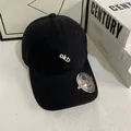 Close-up van zwarte katoenen honkbalpet met wit 'ok!' borduurwerk en een zilverkleurig label - M / Zwart