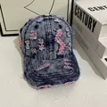 Dettaglio del cappello vintage in denim consumato con finiture in tessuto rosa sfrangiato - M / Denim Blu Con Cuciture Rosa