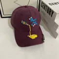 Detail of burgundy baseball cap with blue embroidery and metal bottle opener on brim - M (56-58cm) / Purple