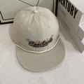 Dettaglio del cappellino beige con visiera piatta, ricamo colorato e cordino bianco decorativo - M (56-58cm) / Bianco Sporco