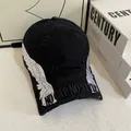 Detail der weißen Flügel-Stickerei und Used-Look Textur auf einer schwarzen Baseballkappe - M / Schwarz