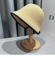 Detail of a beige woven cloche straw hat with black ribbon edge on a wooden stand - M (56-58cm) / Beige