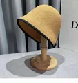 Dettaglio del cappello di paglia intrecciata con bordo nero su supporto in legno - M / Cachi