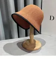 Detailed view of woven straw sun hat in camel with black trim on a wooden display stand - M (56-58cm) / Caramel