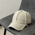 Détail des bords effilochés sur une casquette de baseball vintage blanc cassé - Réglable / Poche zippée