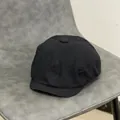 Dettaglio ravvicinato di un cappello newsboy nero in cotone con bottone e cuciture - M(56-58cm) / Nero