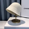 Macro view of white knitted bucket hat with dense wool texture on a gold stand - M (56-58cm) / White