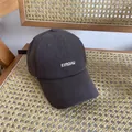 Detailansicht der dunkelgrauen Baumwollkappe mit EIRODAU-Stickerei auf einem Rattanstuhl - M / Grau
