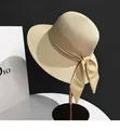 Detail view of the elegant woven straw sun hat with a large bow on a metal stand - M (56-58cm) / Beige