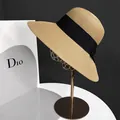 Detailed close-up of woven straw sun hat with black grosgrain ribbon and bow on metal stand - M(56-58cm) / Khaki