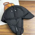 Winterliche schwarze gesteppte Uschanka mit Ohrenklappen und Schnalle auf Holzhintergrund - M / Schwarz