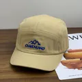 Khaki 5-panel short brim camp hat with blue mountain embroidery on a wooden table - M / Khaki