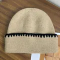Thick khaki striped knit beanie for women with black crochet edge on wooden table - M / Khaki