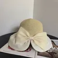 Detail of elegant straw sun hat with large organza bow and wide pleated brim detail - M / Off White