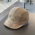 Detail of khaki 5-panel quick-dry hat featuring a yellow woven label and metal eyelets - M / Khaki