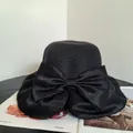 Detail of a black woven straw sun hat with a large satin bow for beach vacations - M / Black