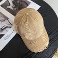 Detail of khaki distressed cotton baseball cap with ripped fraying on wooden surface - M / Khaki