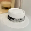 Close-up of a white boater hat with a chic ink-patterned ribbon and pearl trim detailing - M (56-58cm) / White