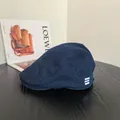 Detail einer dunkelblauen Denim-Schirmmütze mit drei weißen Akzentstreifen auf Strukturstoff - M / Denim Newsboy Mütze / Dunkelblau