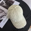 Close-up of a distressed cotton baseball cap with ripped details on black wood - M / White