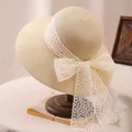 Detail of beige straw sun hat with large white lace bow on a vintage wooden stand - M (56-58cm) / Beige