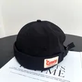 Detail of black docker hat featuring adjustable strap and camping patch on textured fabric - M(56-58cm) / Black