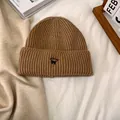 Detalle del gorro de punto marrón con bordado de gato negro sobre tejido de canalé grueso - M / Caqui