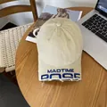 Detail of embroidered MADTIME logo on distressed cotton baseball cap with frayed brim - M / Beige