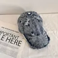 Dettaglio del cappello da baseball in denim lavato con fori consumati e bordi sfilacciati - M (56-58cm) / Blu scuro