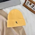 Detail of a bright yellow knitted beanie with a black embroidered letter R on the cuff - M / Yellow