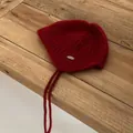 Detail of red mohair knit hat with ear flaps, metal logo tag and braided ties on wood - M (56-58cm) / Red