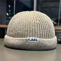 Close-up of the oatmeal grey ribbed knit texture and FJMS woven label on the miki hat - M / Khaki