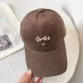 Detail view of the smile embroidery and fine stitching on the brown cotton baseball cap - M (56-58cm) / Coffee