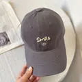 Close-up of white Smile text and face embroidery on a dark grey cotton baseball cap - M (56-58cm) / Gray